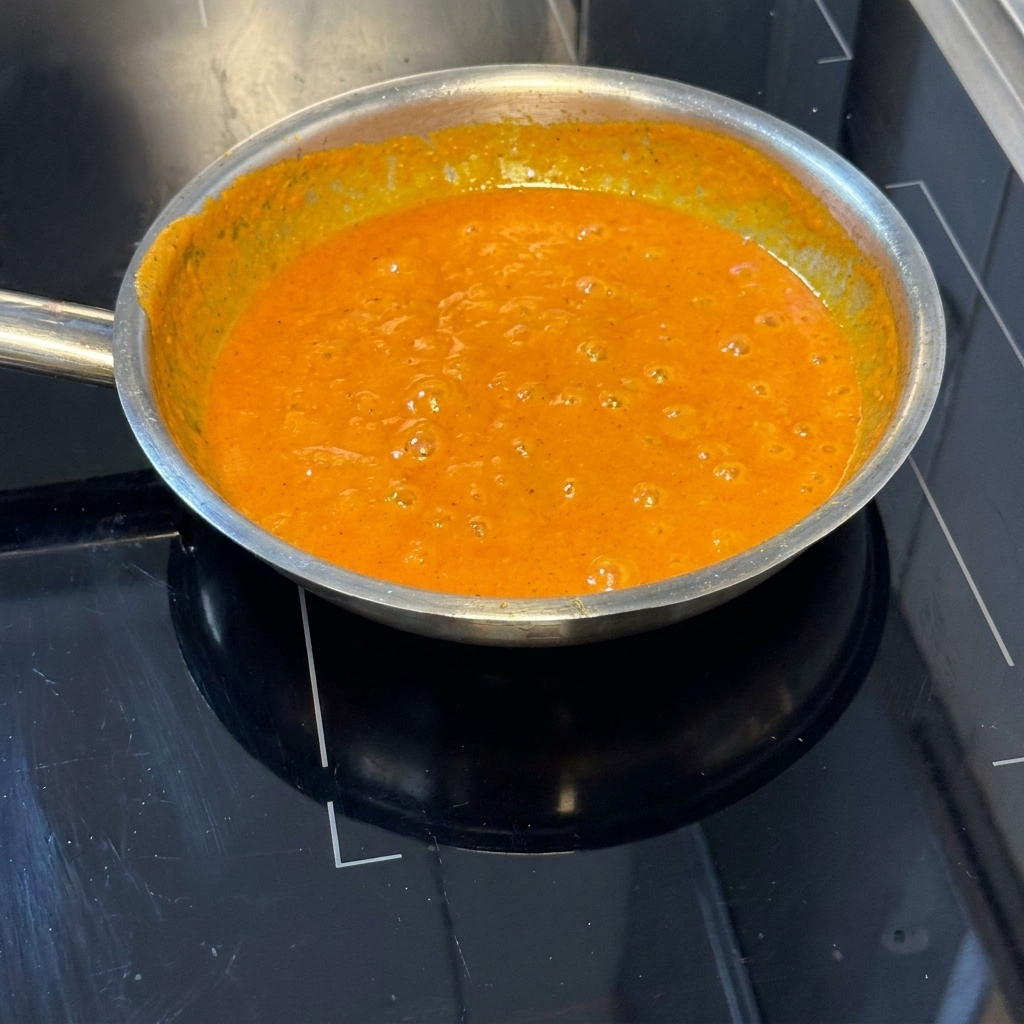 Pâtes cuites mélangées dans la sauce orange vif au poivron dans la poêle.