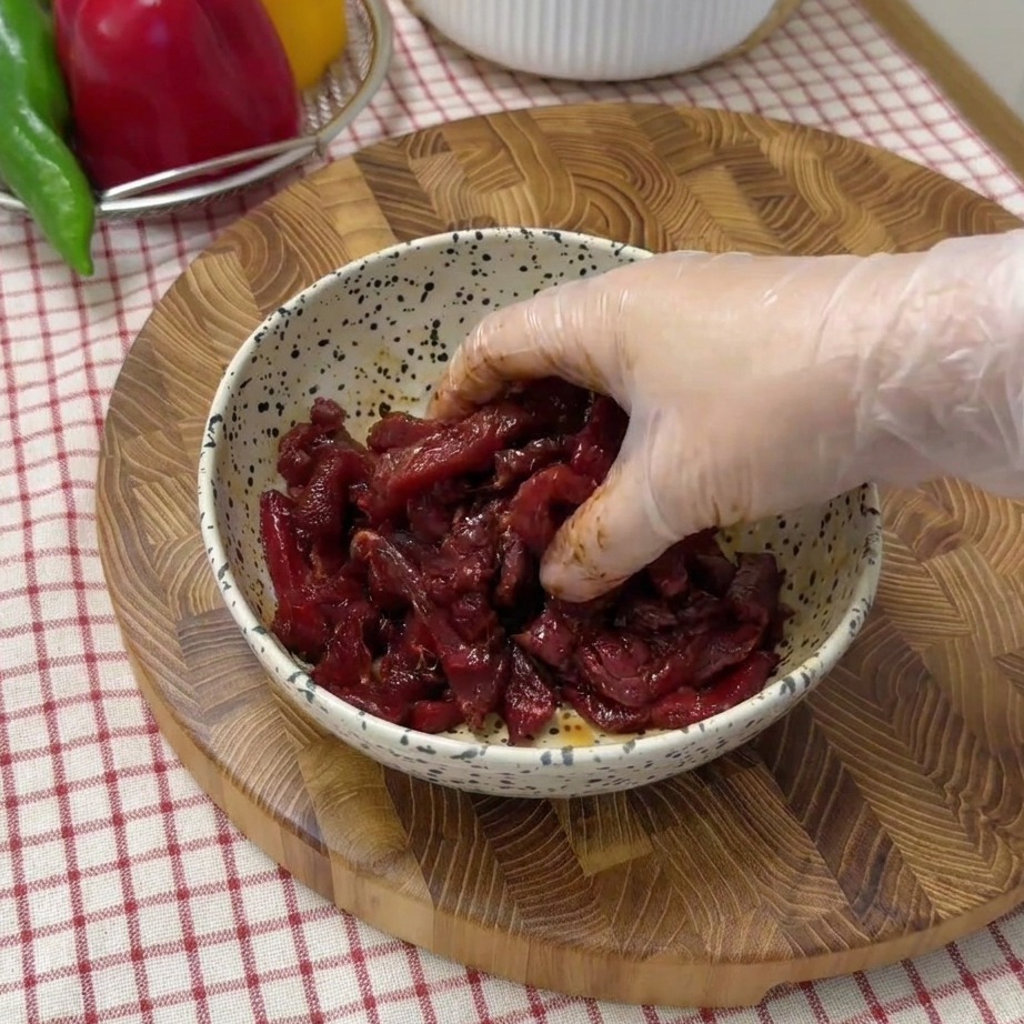Lanières de bœuf en train de mariner dans un bol avec de la sauce soja et des épices.