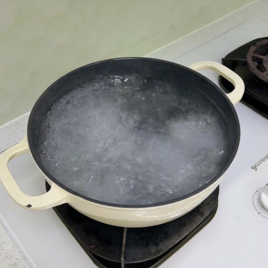 Pâtes rotini sèches versées dans une casserole deau bouillante.