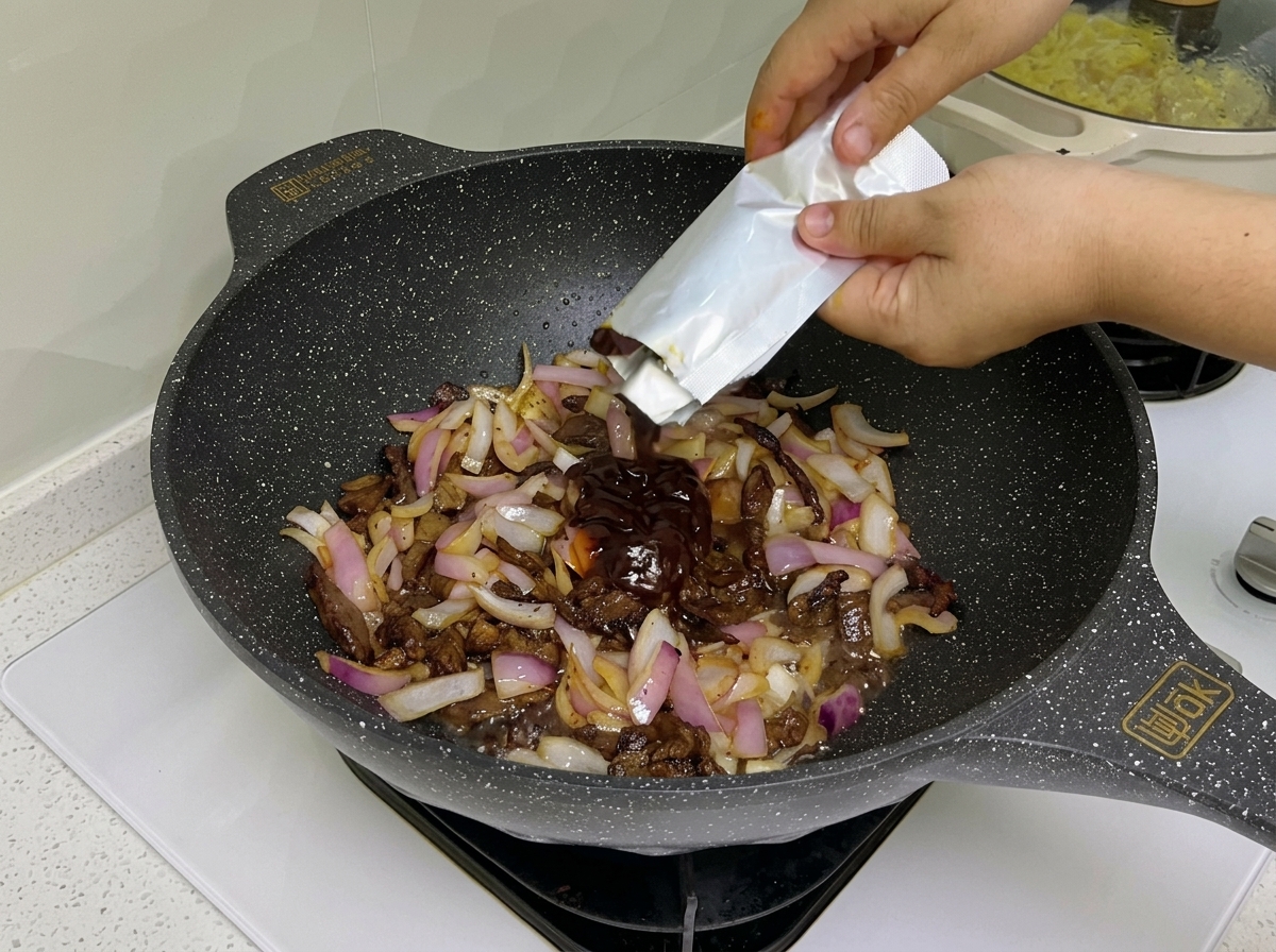 Sauce pour pâtes et concentré de tomate incorporés dans le wok avec le bœuf et les oignons.