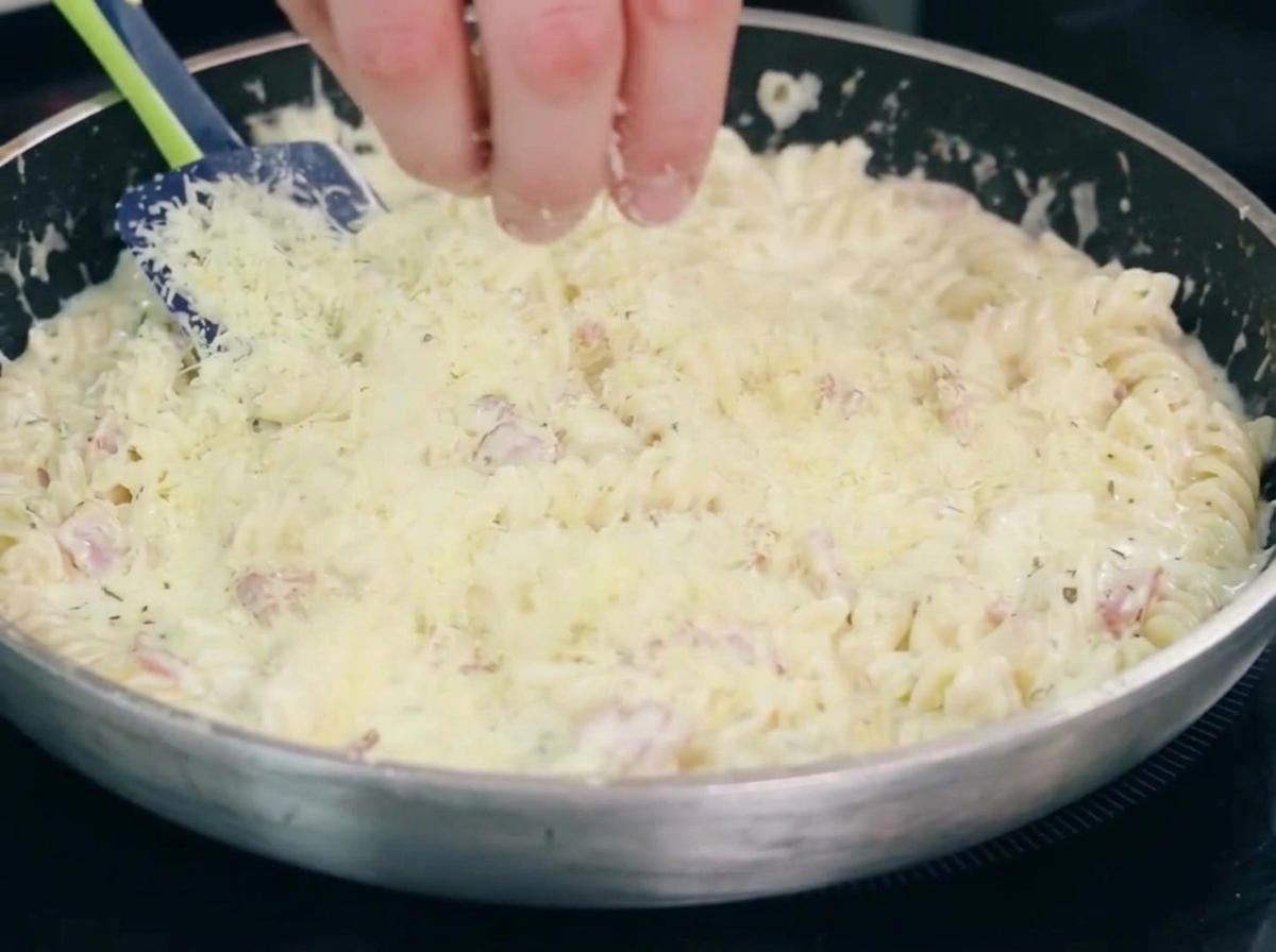 Des oignons et de lail qui cuisent avec le bacon dans une poêle.