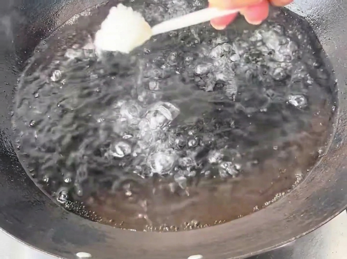 Une cuillère de sel versée dans un wok en fer rempli deau bouillante.