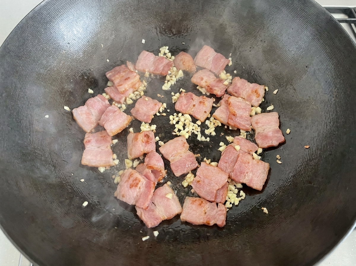 Champignons de Paris émincés ajoutés dans le wok avec le mélange bacon et ail.