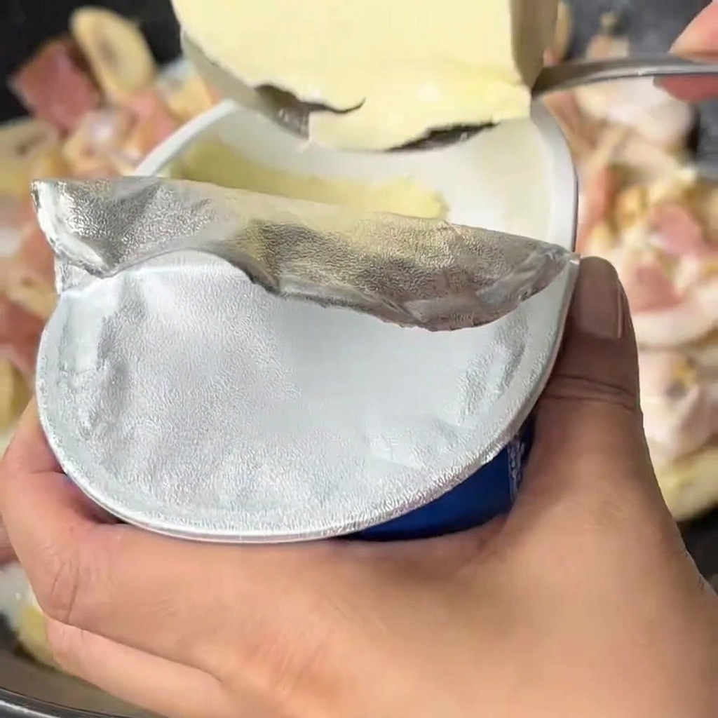 Fromage frais ajouté dans la sauce au lait bouillonnante dans le wok.