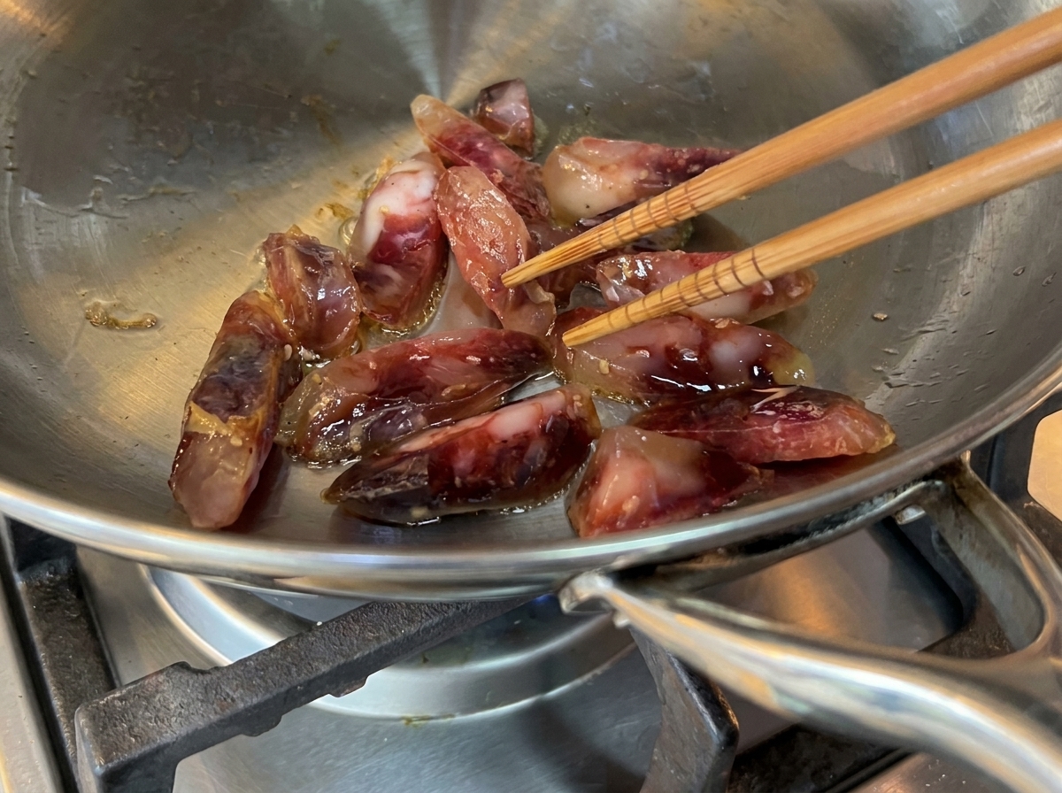 Morceaux de viande crépitant dans une poêle en inox avec de lhuile dolive.