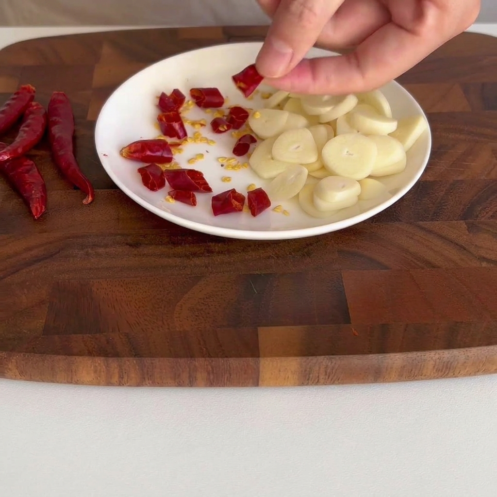 Petits morceaux de piment rouge séché éparpillés sur une petite assiette blanche.