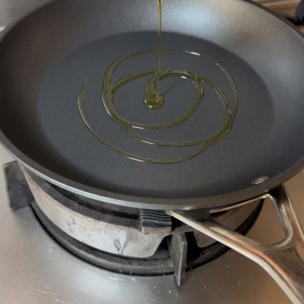 Un filet dhuile dolive dorée se déposant au fond dune poêle noire.