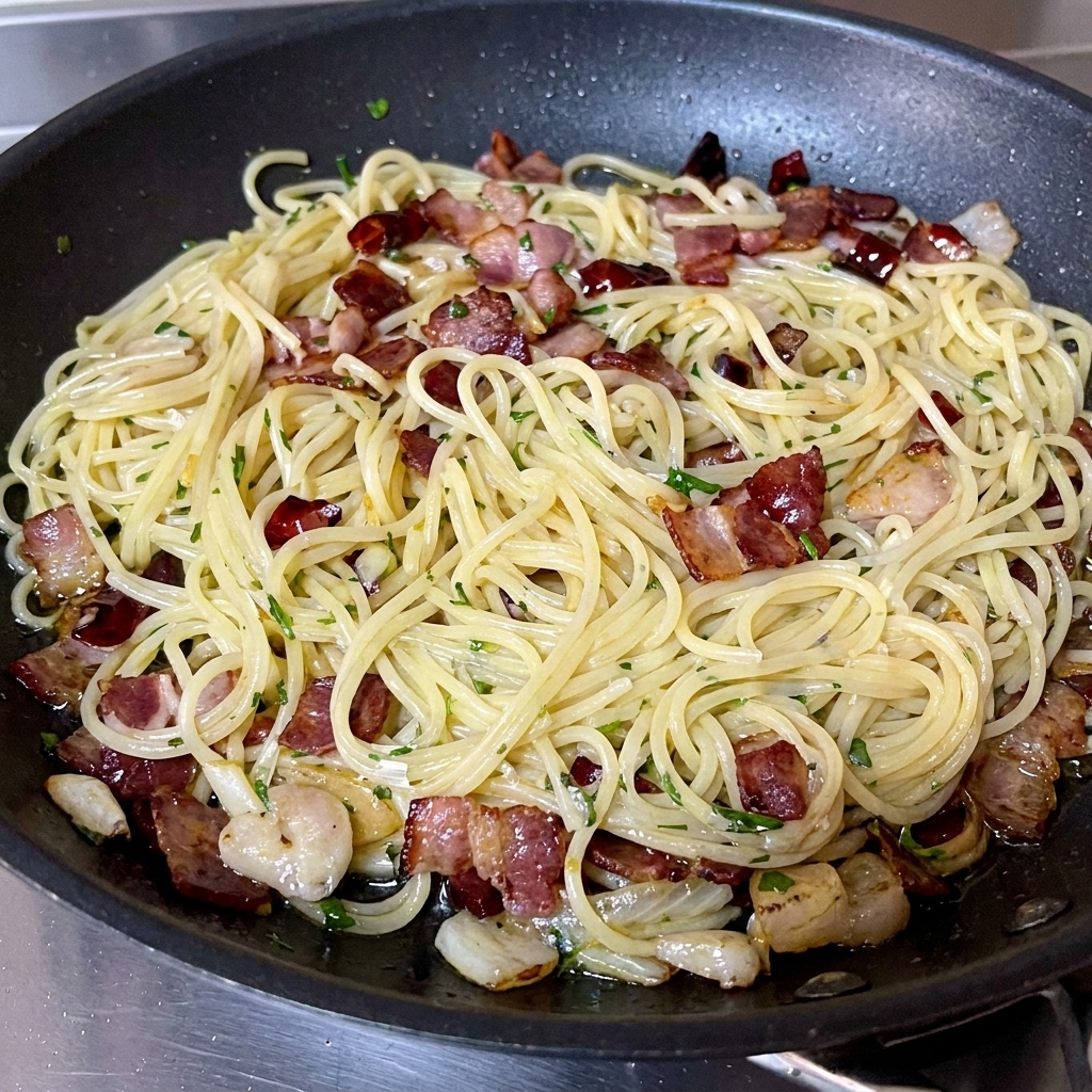 Persil vert fraîchement haché saupoudré sur une poêle de spaghettis au bacon terminée.