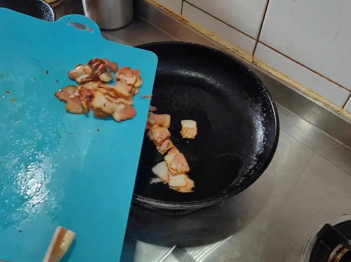 Tranches de lard cru ajoutées dans une poêle chaude avec de lhuile dolive.
