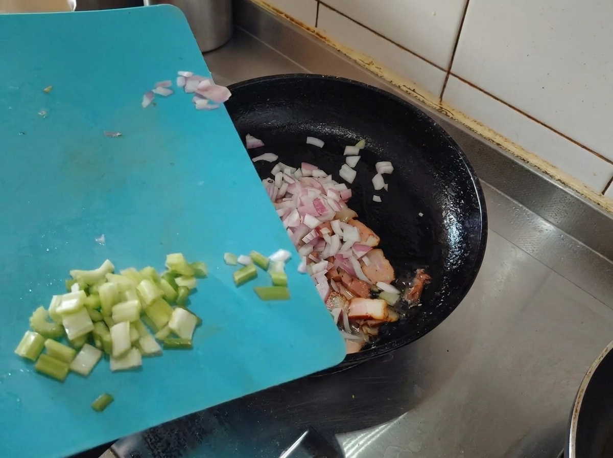 Échalotes et céleri hachés ajoutés dans la poêle avec le lard doré.