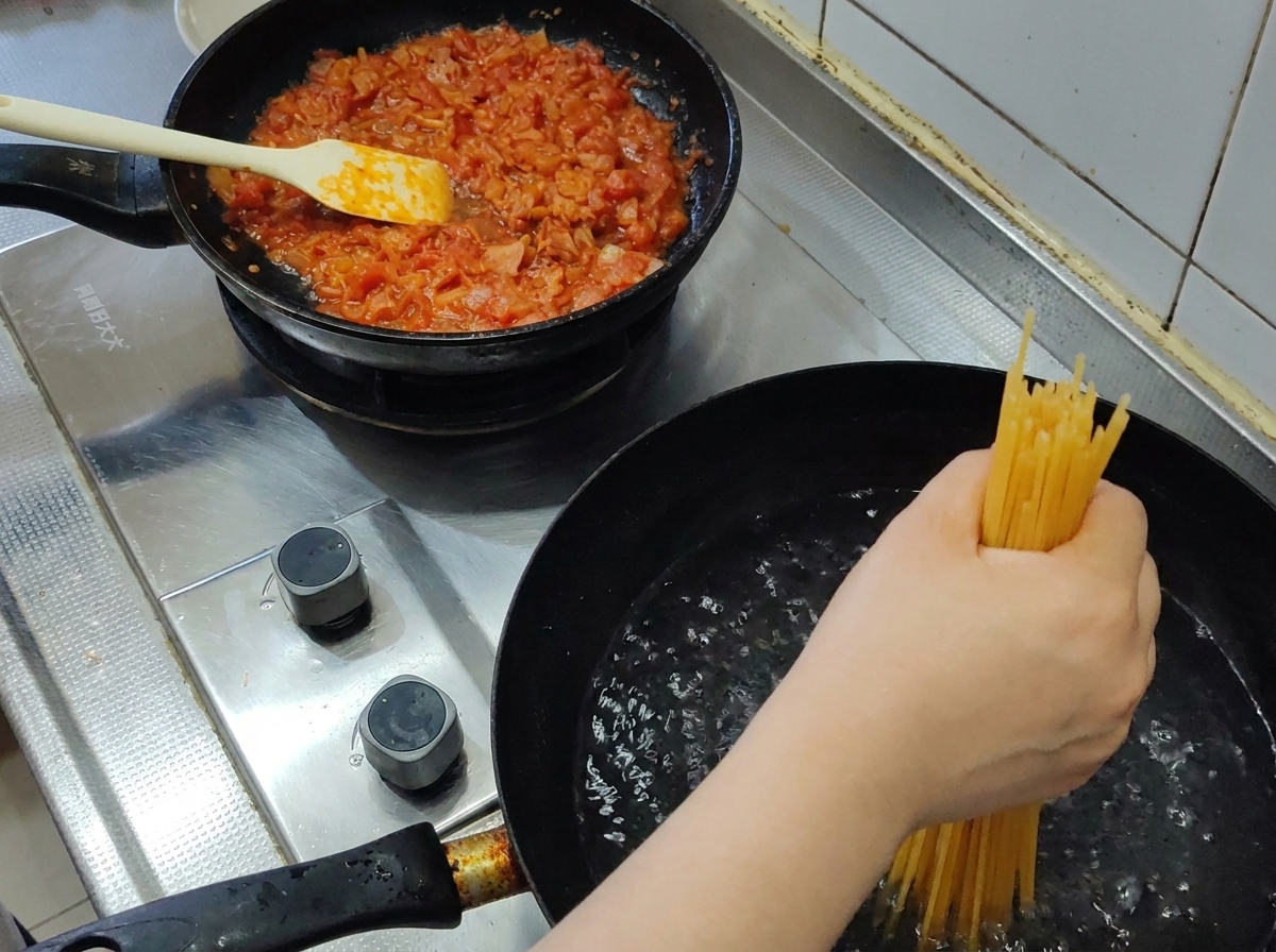 Une poignée de spaghetti secs plongés dans une casserole deau bouillante.