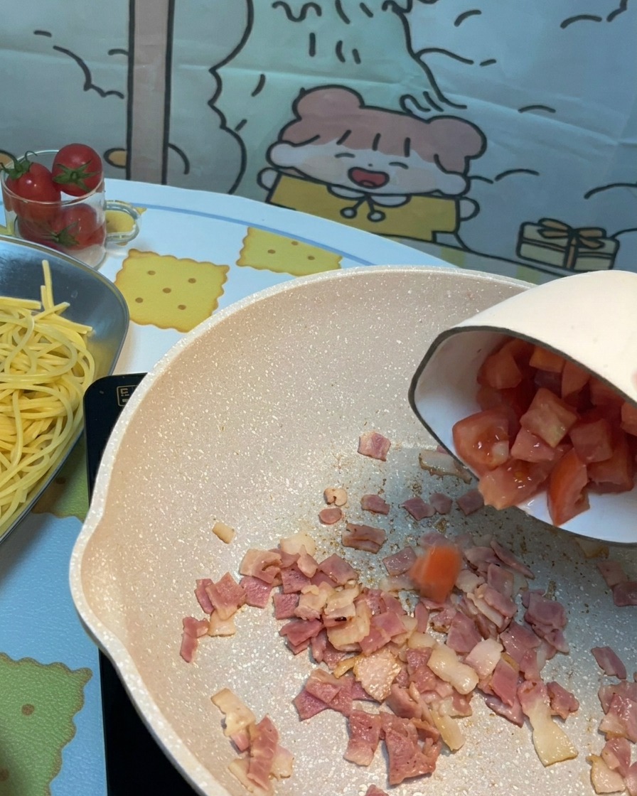 Tomates coupées ajoutées dans la poêle avec le bacon croustillant.