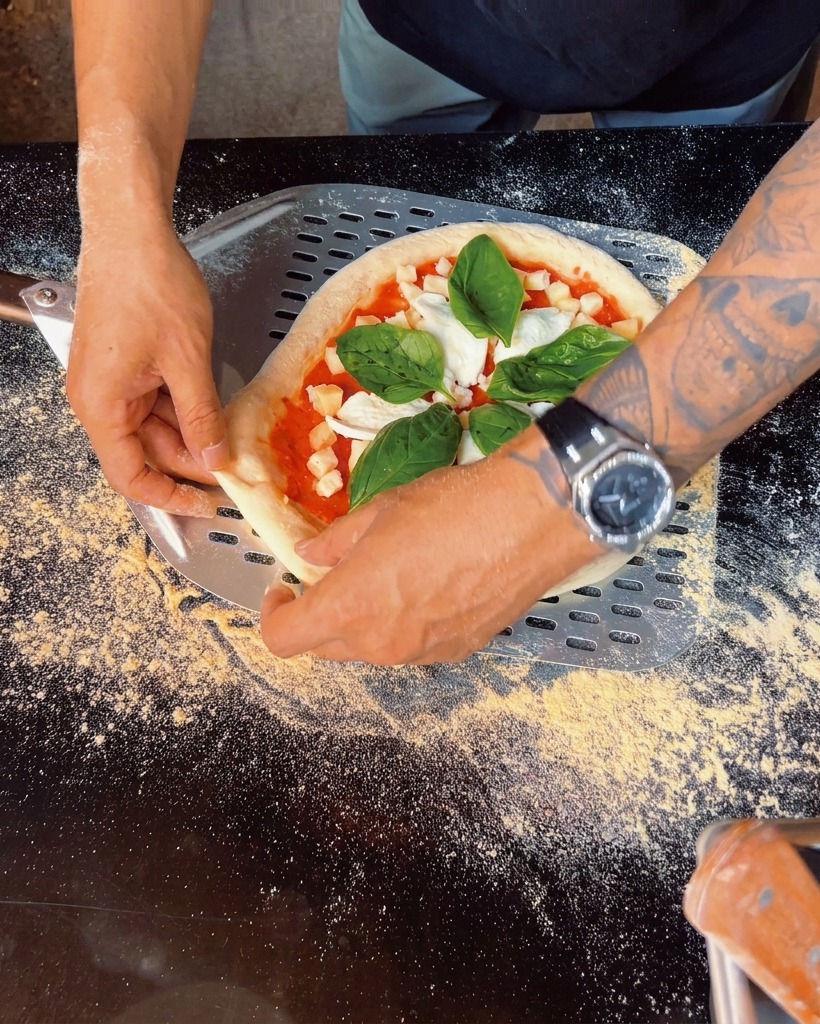 Gros plan de feuilles de basilic frais déposées sur la pizza préparée.