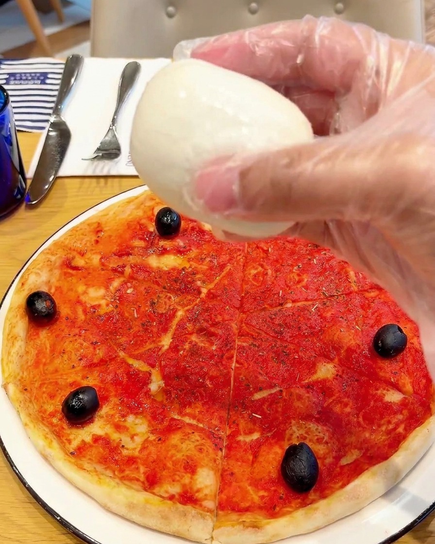 Morceaux de mozzarella di bufala déposés sur la pizza.