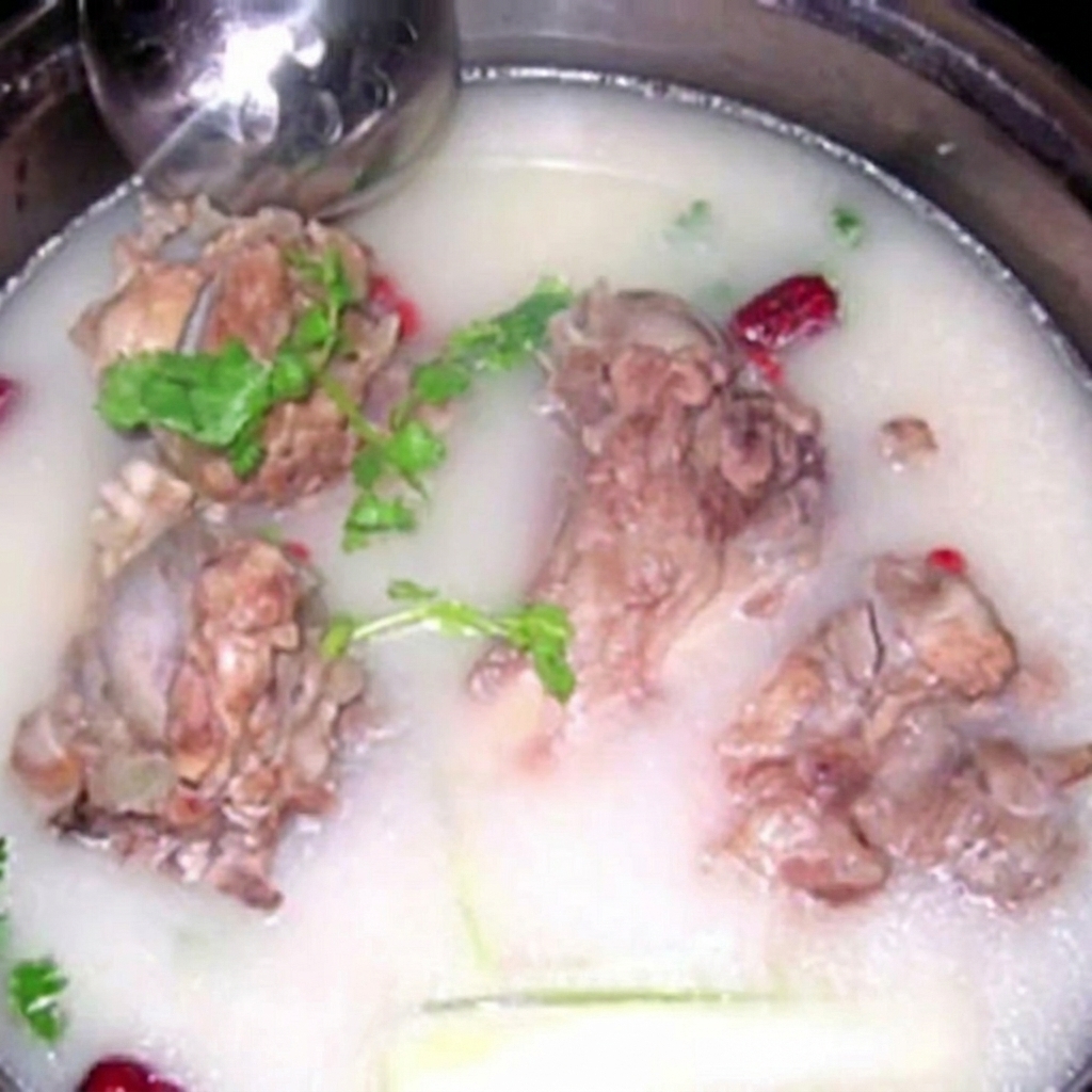 Plusieurs gros os de porc immergés dans un bouillon laiteux et opaque, garni dherbes fraîches.