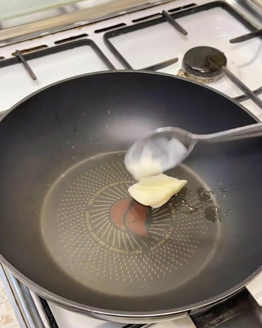 Une cuillère de saindoux blanc fondant dans une poêle noire chaude.