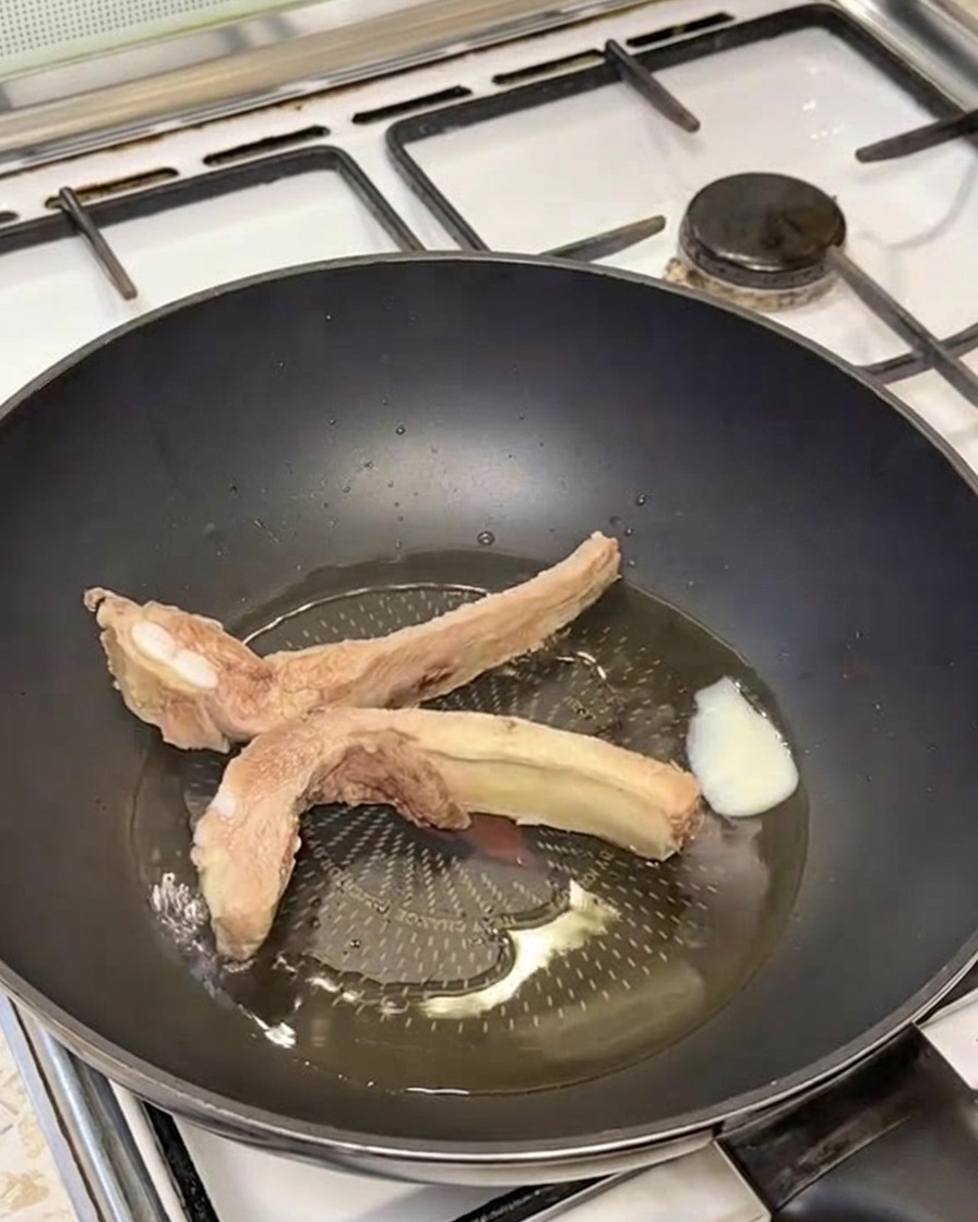 Travers de porc dorés grésillant dans une poêle avec du saindoux fondu.