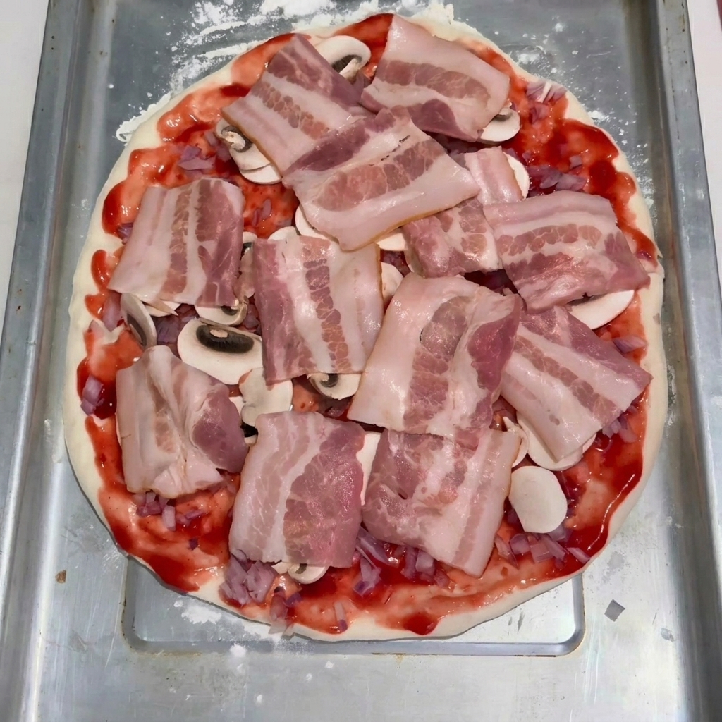 Tranches de bacon cru disposées soigneusement sur une couche de champignons et de sauce tomate sur la pâte à pizza.