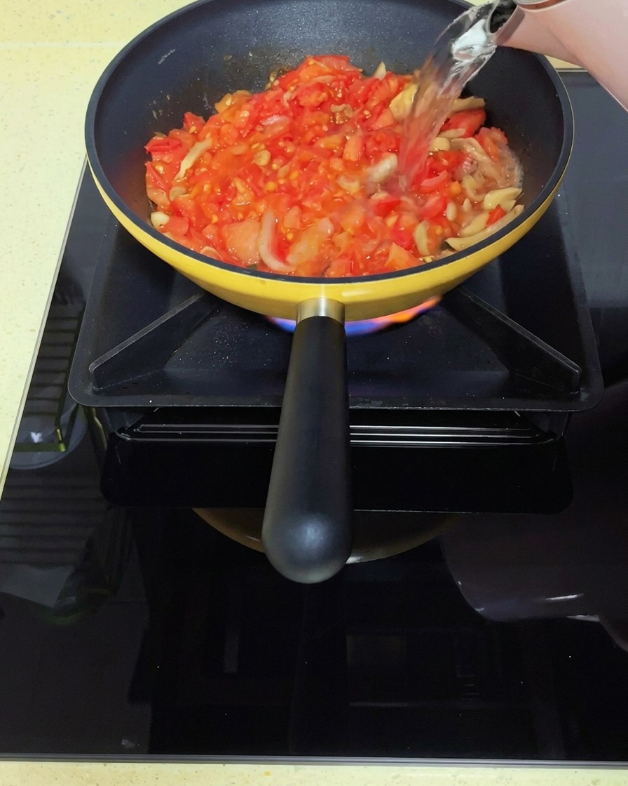 Eau bouillante versée sur la base de tomates et de légumes marinés.