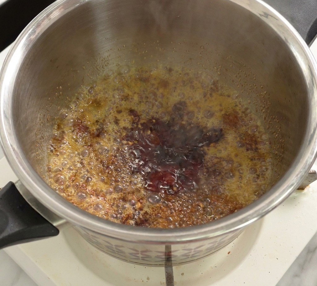 Mélange de sauce tomate et de vinaigre frémissant dans une casserole sur le feu.