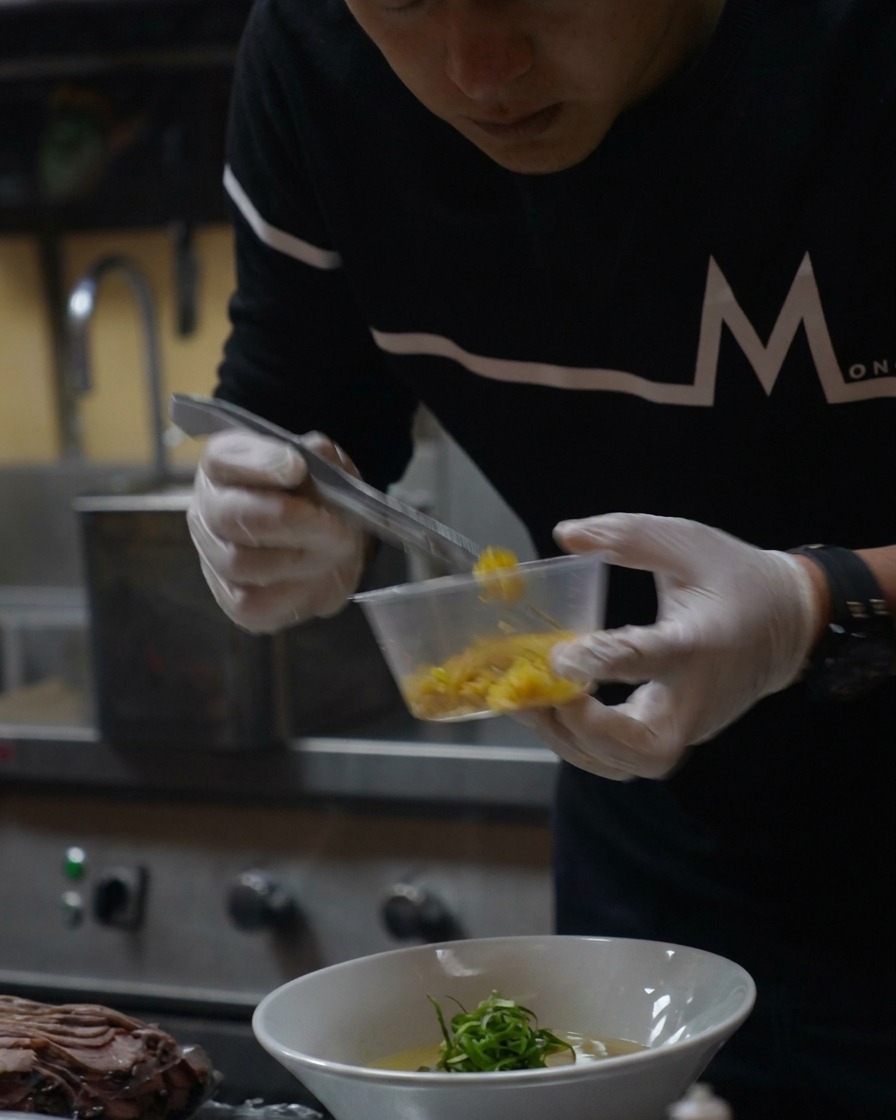 Une petite cuillère de zeste de yuzu jaune vif saupoudrée sur le ramen terminé.