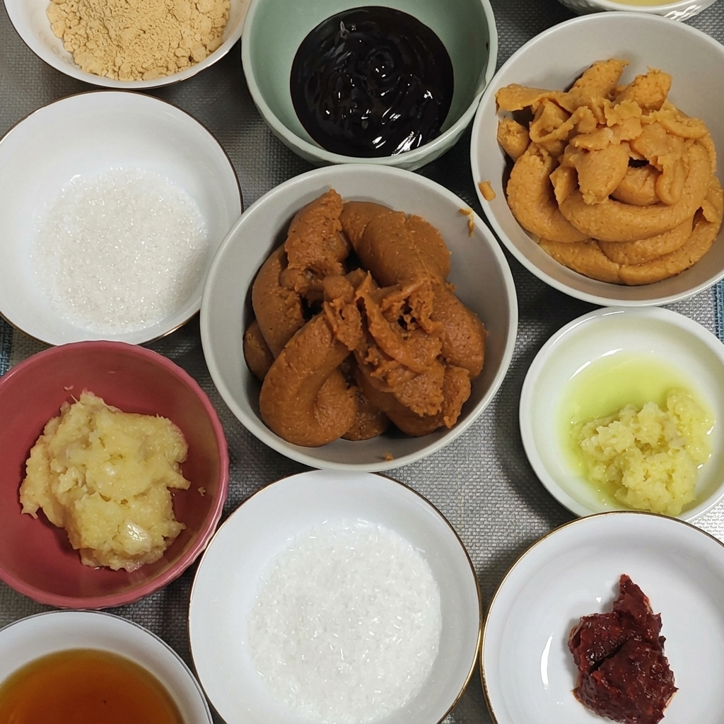 Une grosse cuillère de pâte miso rouge épaisse déposée dans un bol avec de lail et du gingembre.