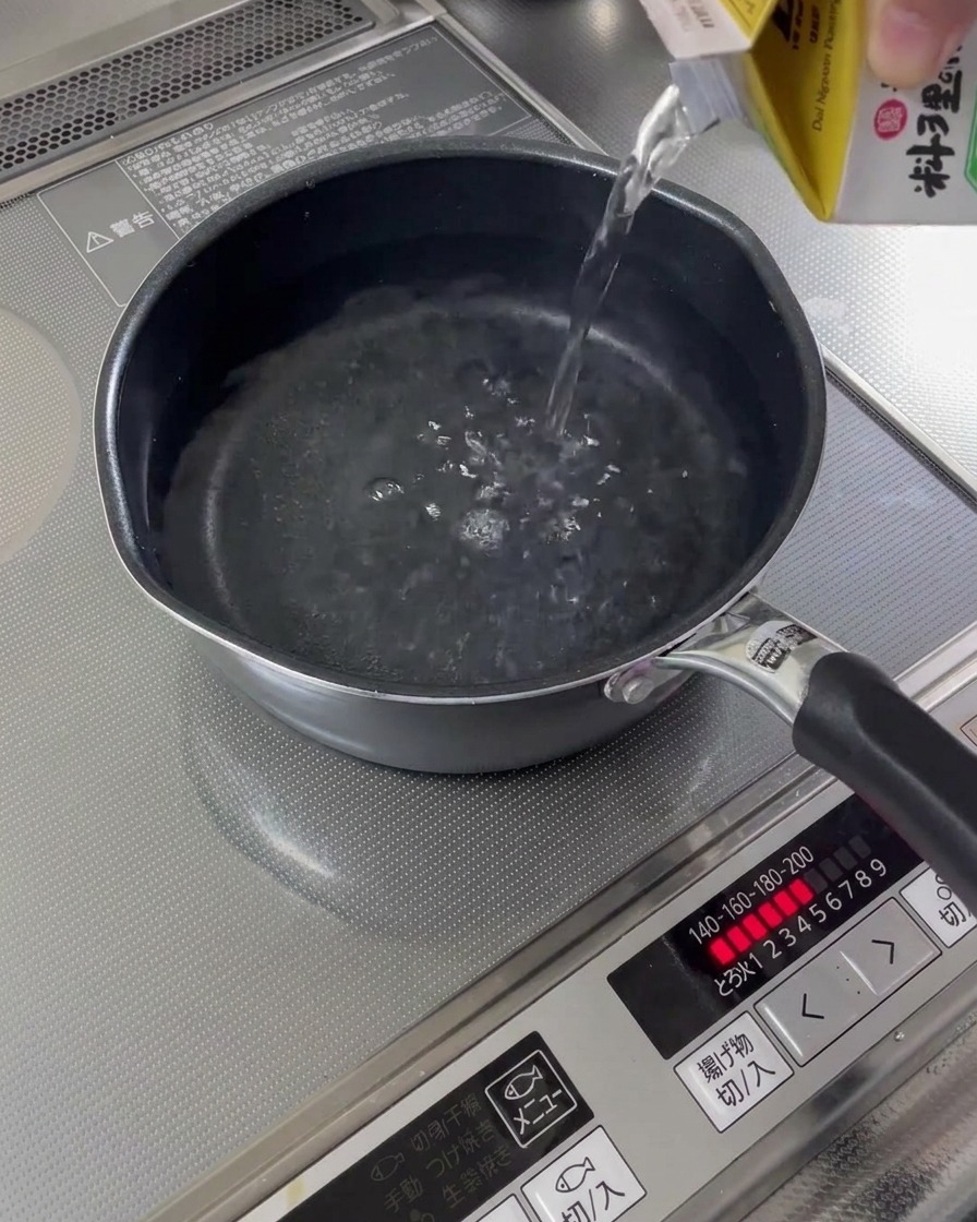 De leau est versée dune carafe dans une petite casserole sur la cuisinière.