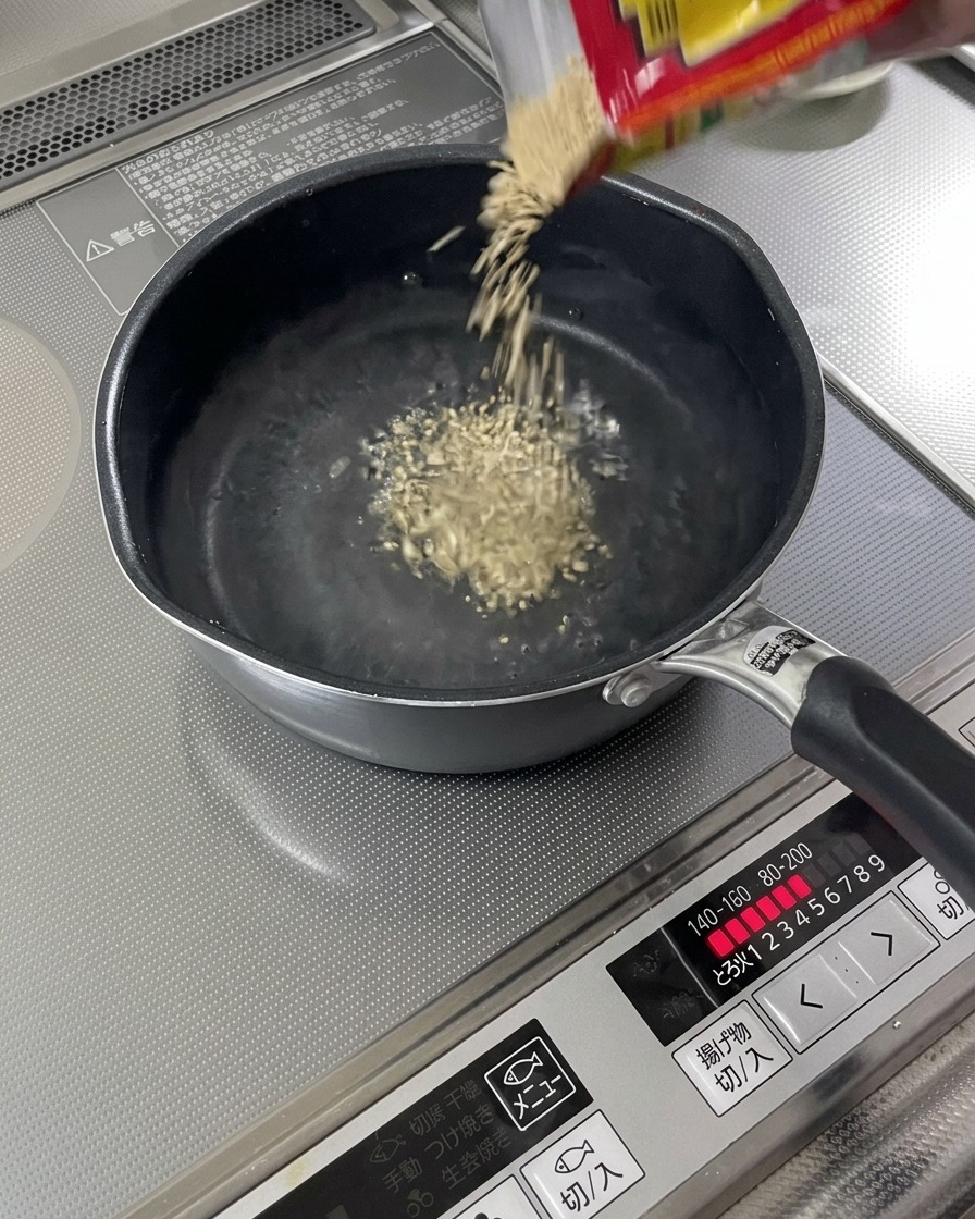 Graines de sésame grillées tombant dans un liquide frémissant.