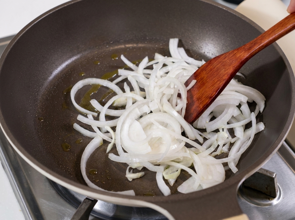 Des lanières doignon blanc sautées dans une poêle huilée avec une spatule en bois.