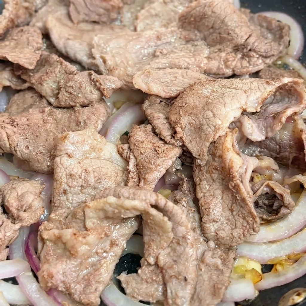 Sauce teriyaki versée sur le bœuf et les oignons.