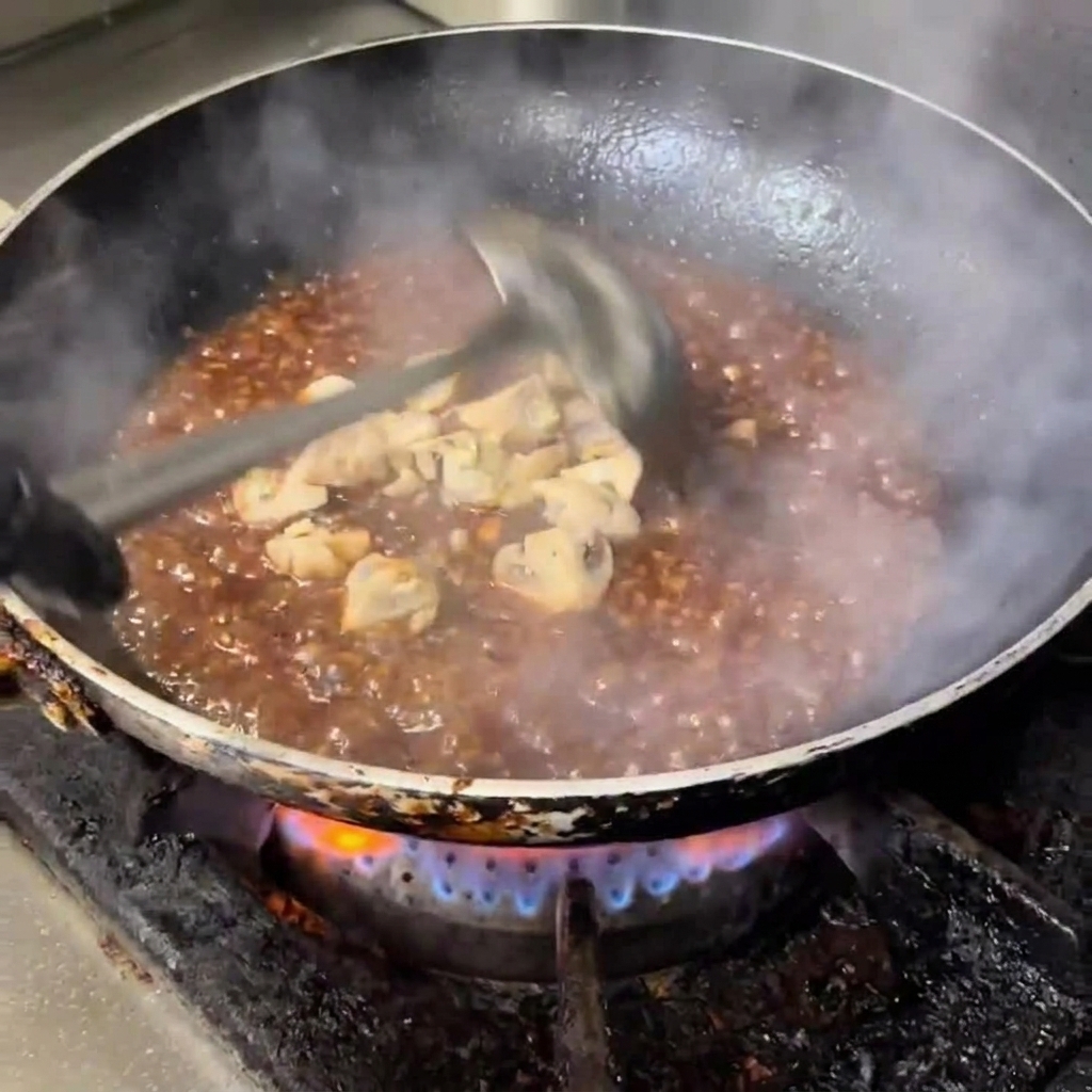 Champignons de Paris coupés en dés mijotant dans une sauce brillante, sombre et savoureuse.