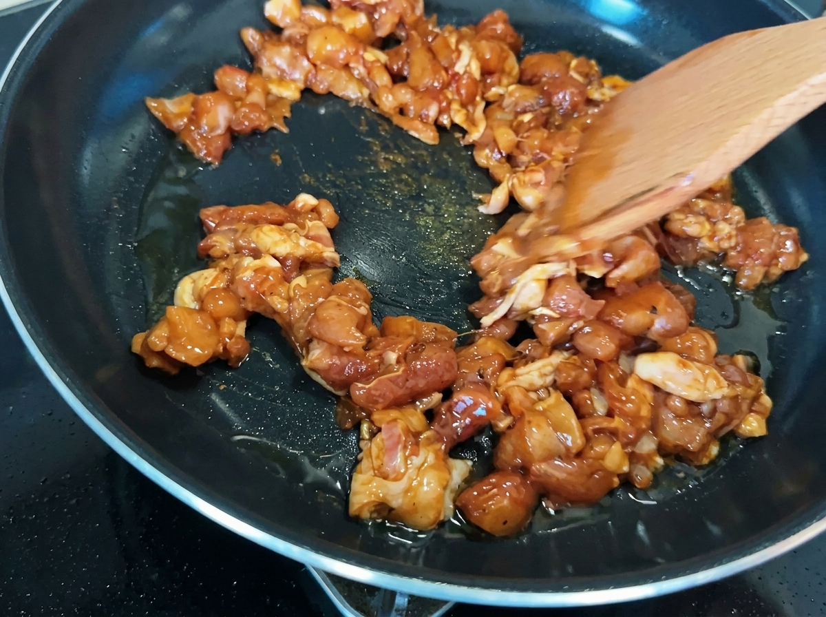 Morceaux de poulet sautés dans une poêle, montrant une caramélisation dorée.