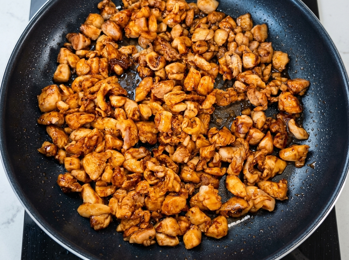 Oignons nouveaux hachés jetés dans la poêle avec le poulet doré.