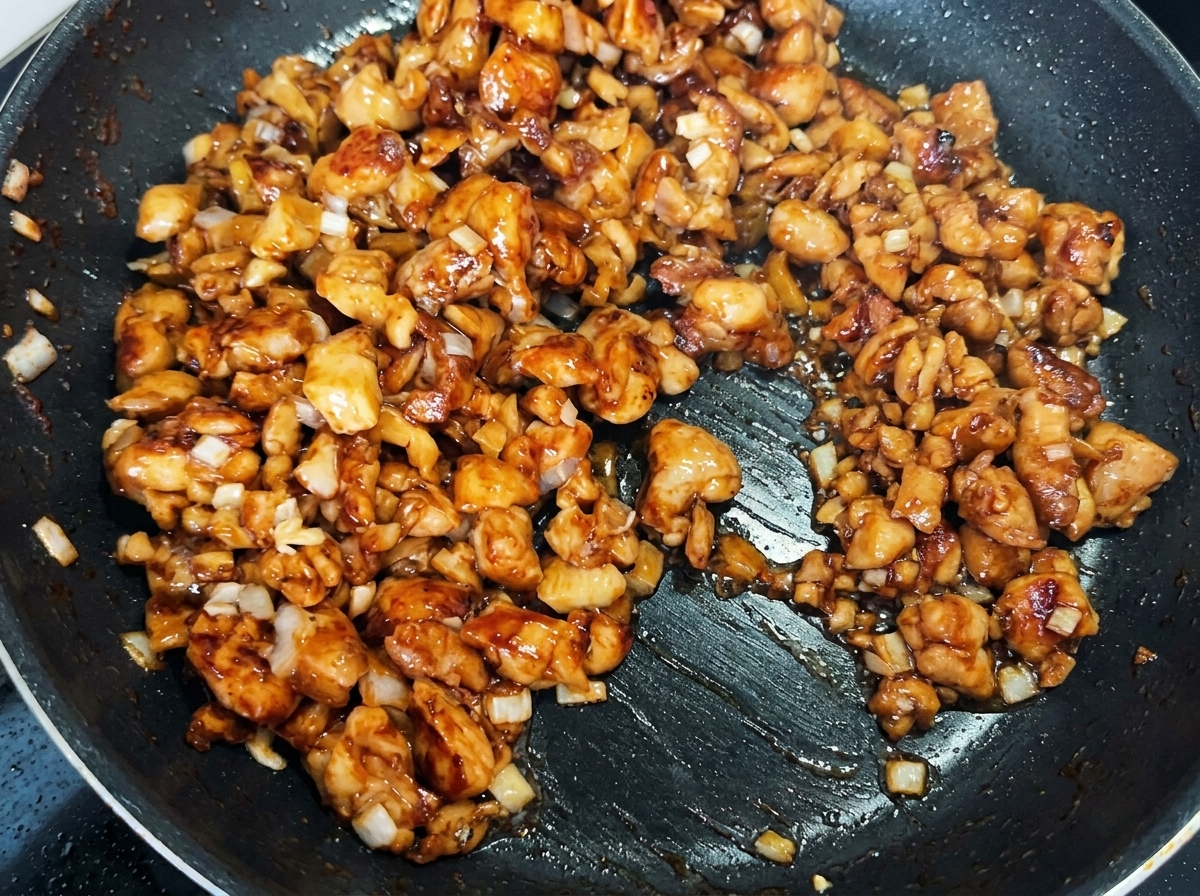 Feuilles de moutarde hachées mélangées avec le poulet et les oignons dans la poêle.
