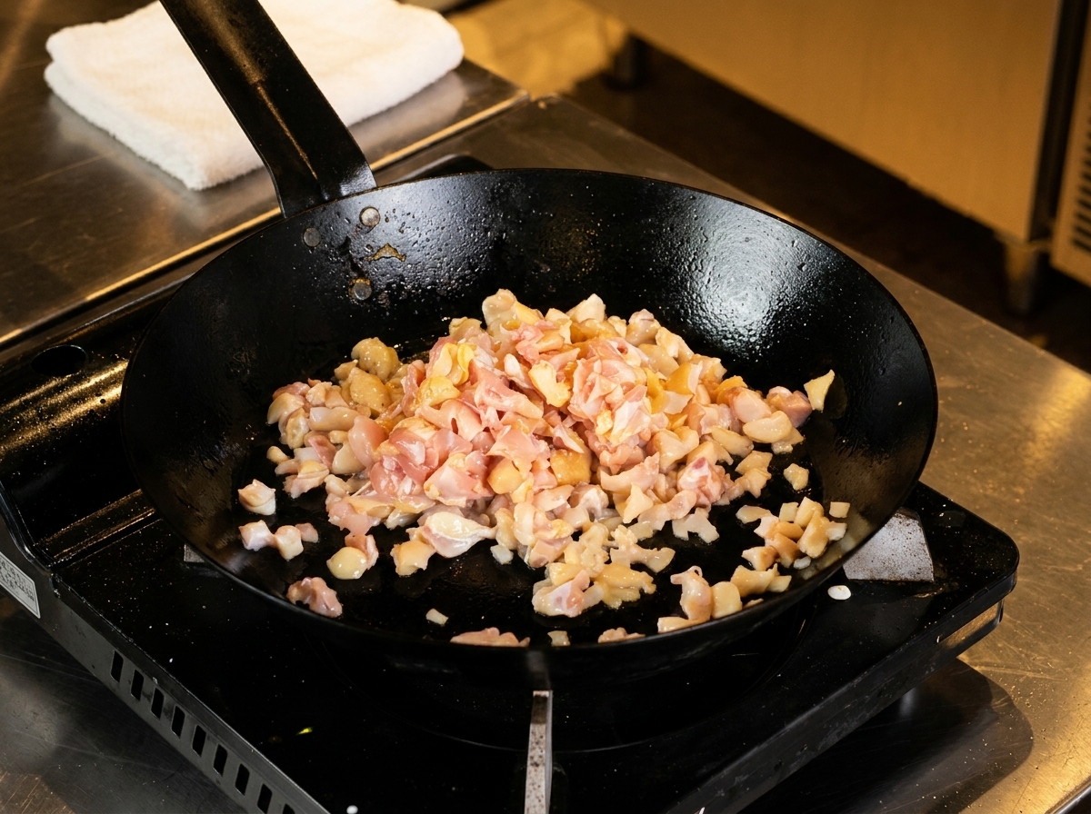Poulet haché et cartilage en train de cuire dans une poêle noire chaude.