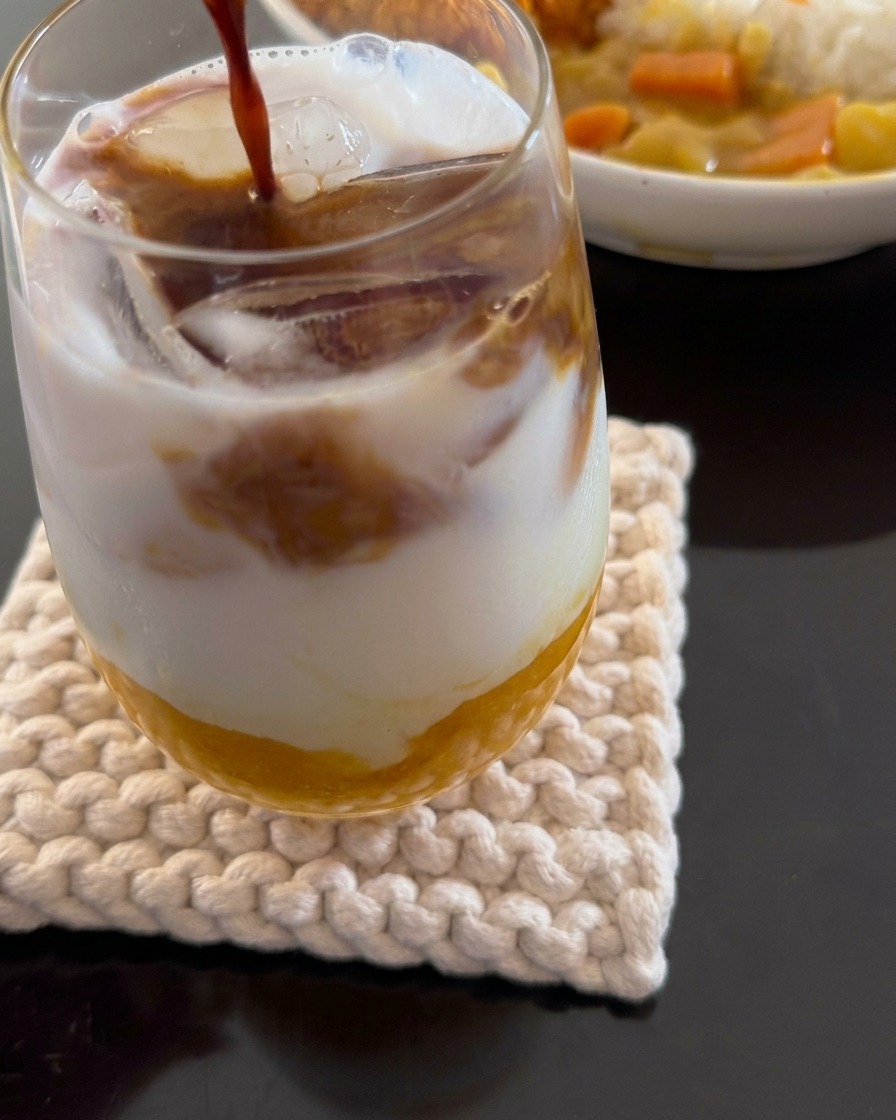Gros plan montrant un expresso versé sur une boisson étagée composée de pulpe de mangue, de lait de coco et de glace.