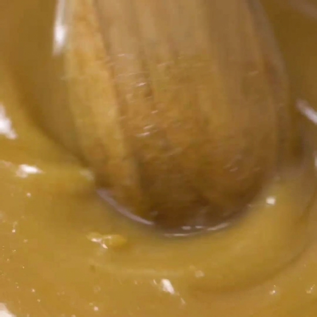 Une cuillère en bois mélangeant la marinade miso dorée dans un bol jusquà obtenir une texture uniforme.