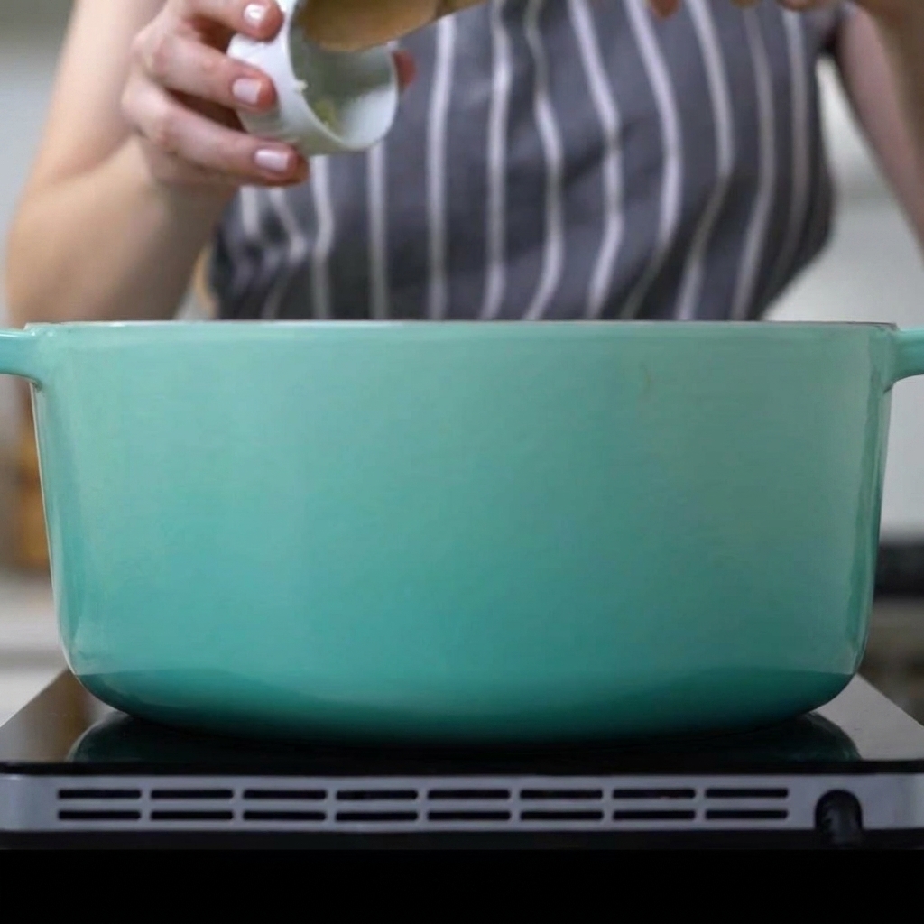 De lail haché ajouté dans une cocotte contenant les travers de porc dorés et les oignons tendres.