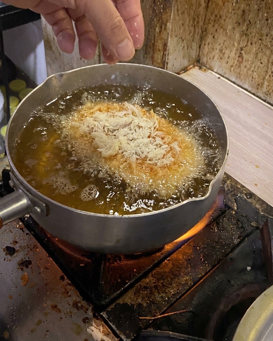 Une côtelette panée plongée dans une huile bouillante.