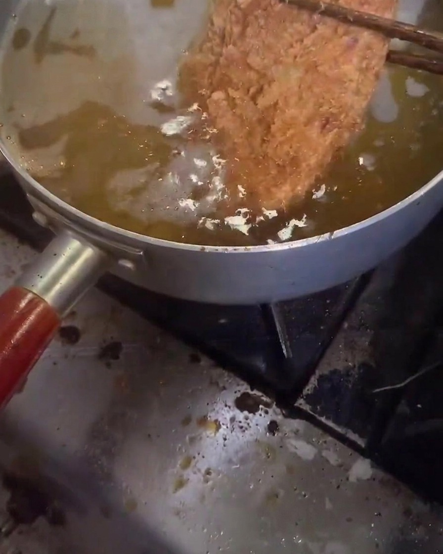 Une côtelette de porc en train dêtre frite pour la seconde fois.