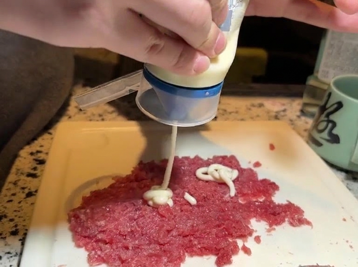 Presser de la mayonnaise blanche sur une portion de thon rouge haché.