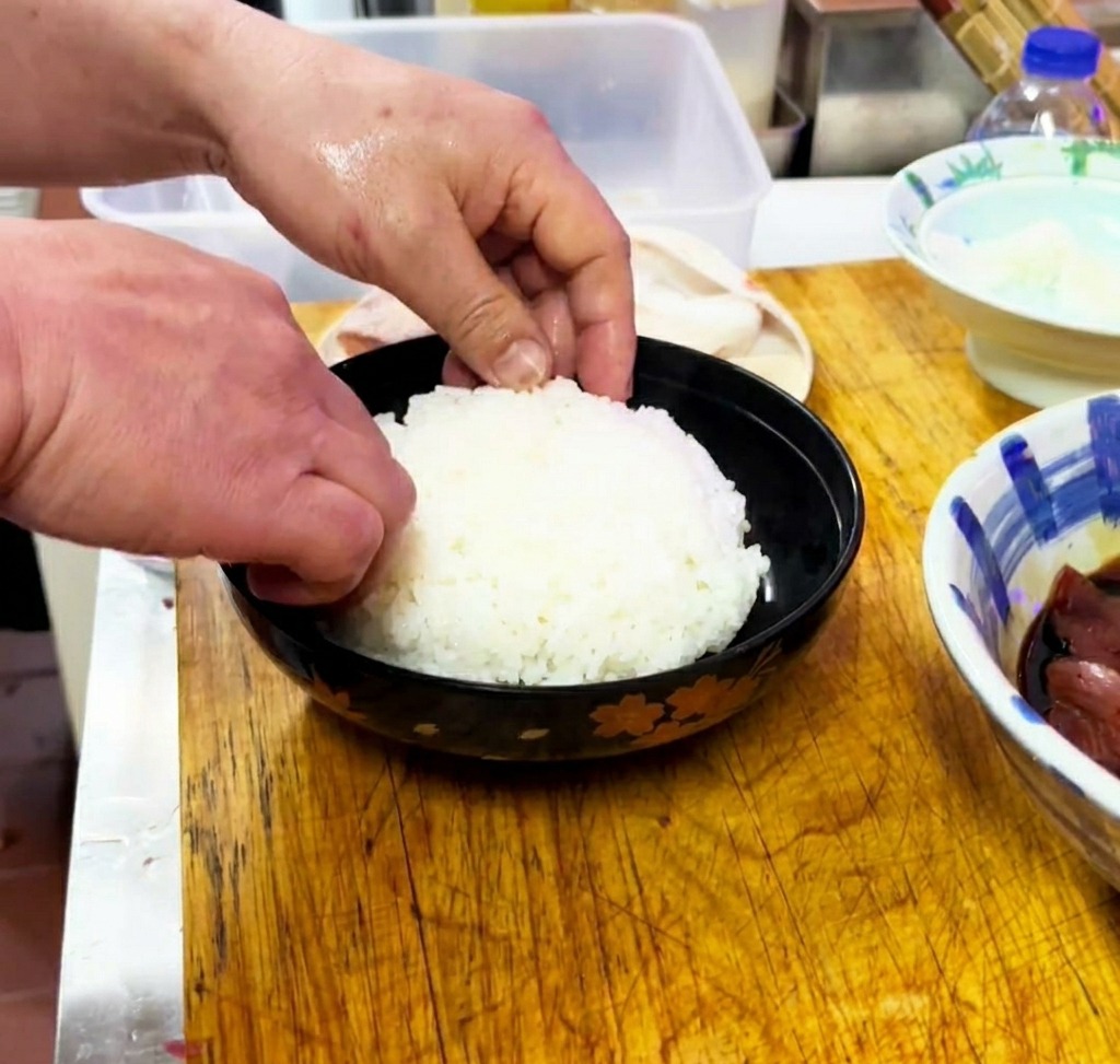 Riz blanc cuit doucement pressé dans un bol noir.
