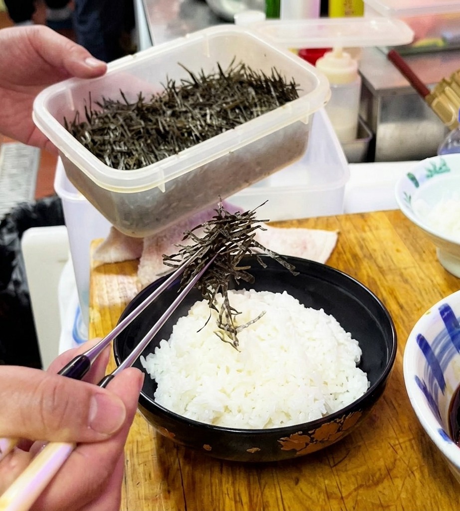 Algues nori ciselées saupoudrées sur un bol de riz blanc.