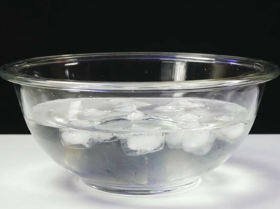 Un bloc de thon plongé dans un bol en verre rempli deau glacée.