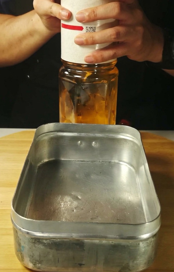 Un liquide clair versé dans un plateau métallique rectangulaire.
