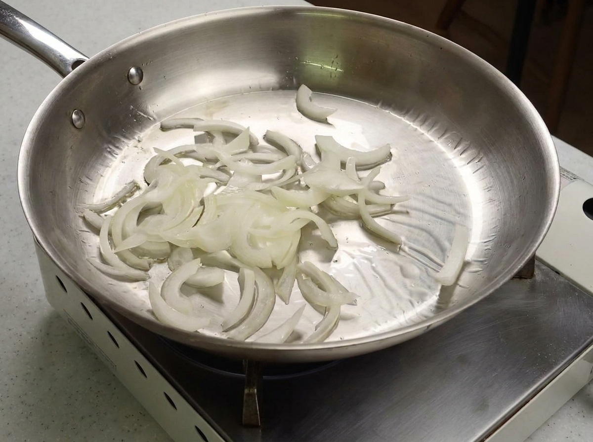 Lamelles doignon blanc sautées dans une poêle en inox brillante.