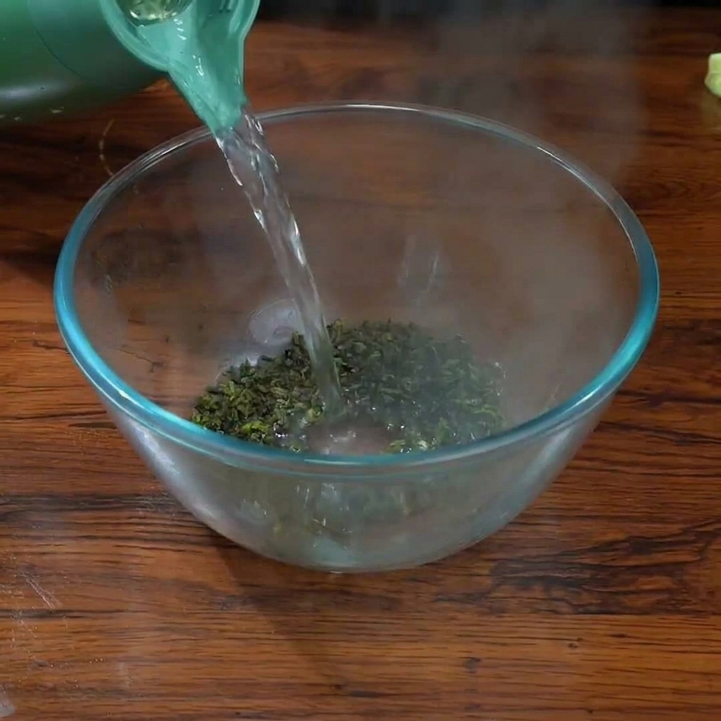 Verser de leau bouillante dune bouilloire verte sur des feuilles de thé Tieguanyin dans un bol en verre transparent.