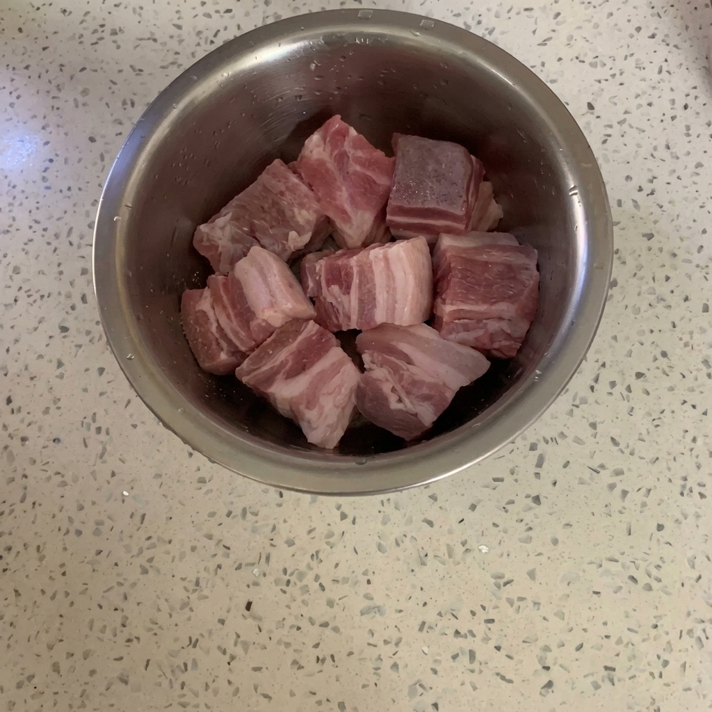 Bol métallique contenant la viande crue saupoudrée de poivre en poudre.