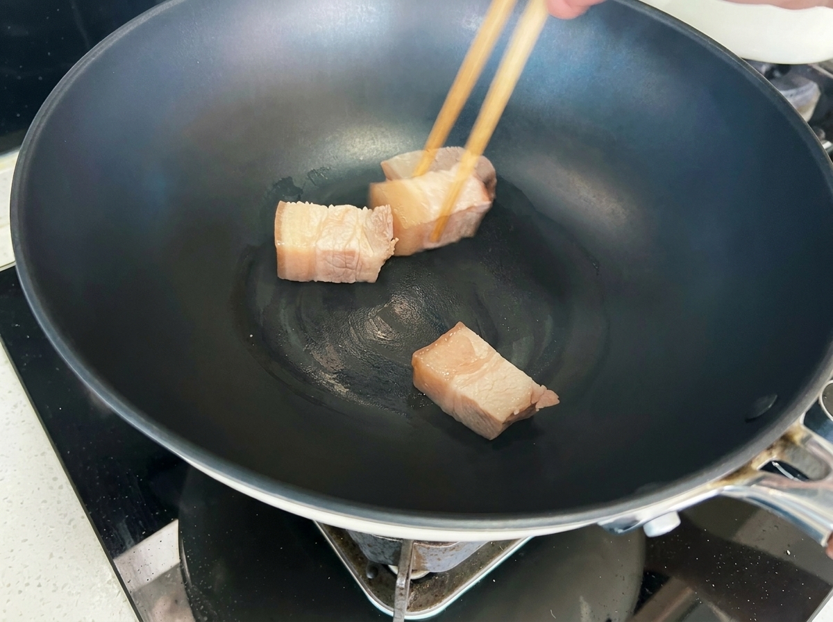 Cubes de porc en cours de saisie dans un wok jusquà ce quils deviennent dorés.