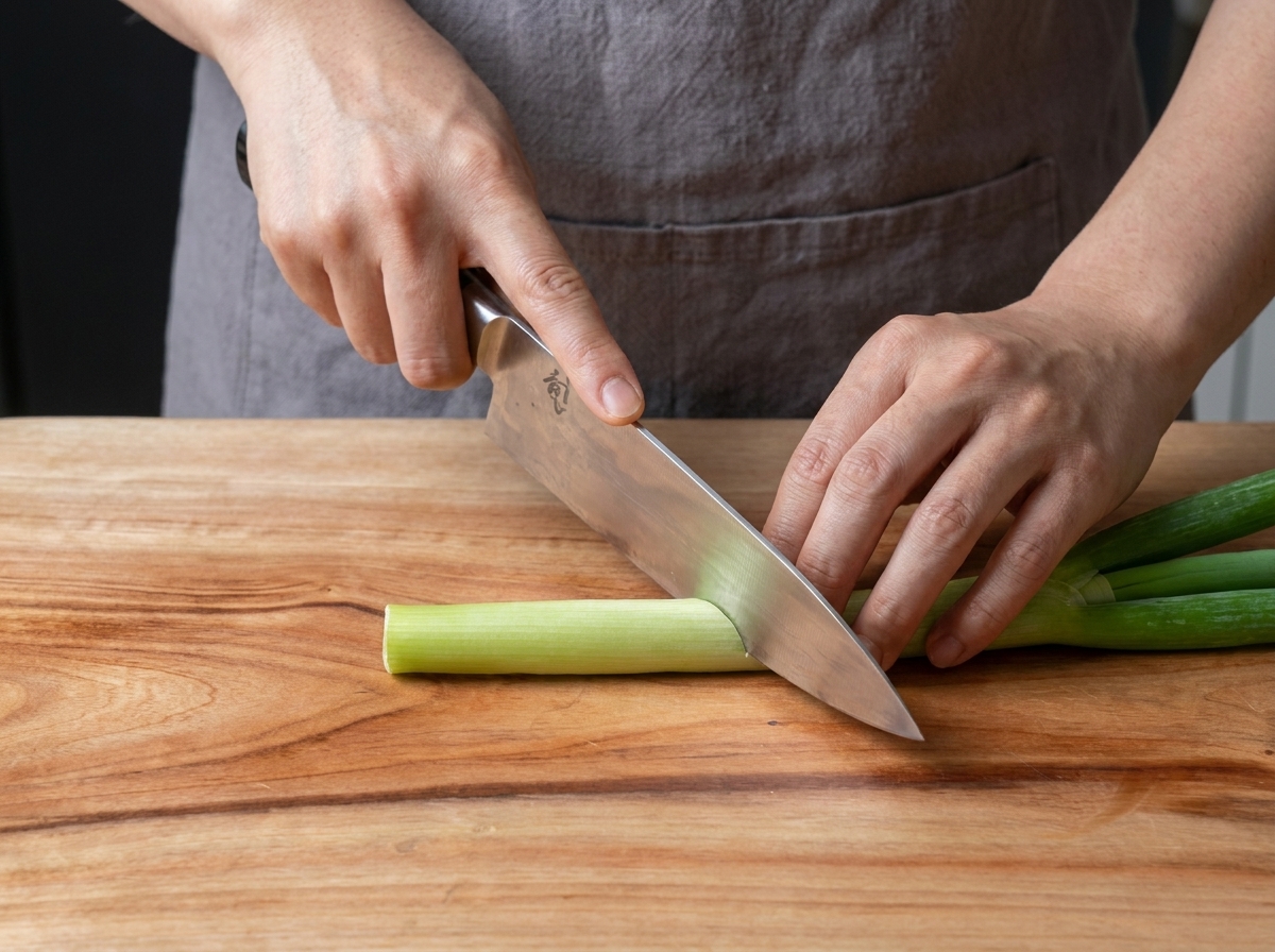 Oignons verts frais émincés sur une planche à découper en bois.
